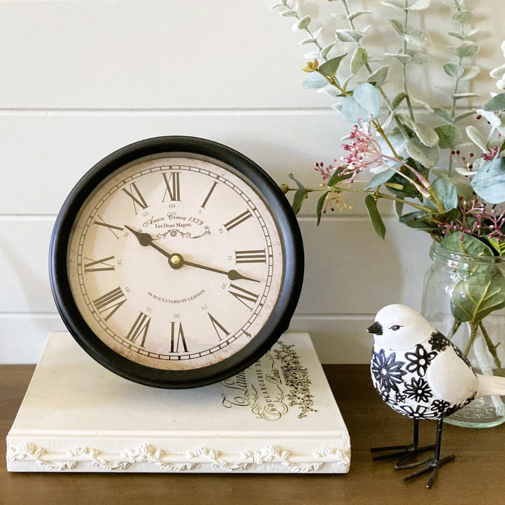 antique metal clock with round face and roman numerals